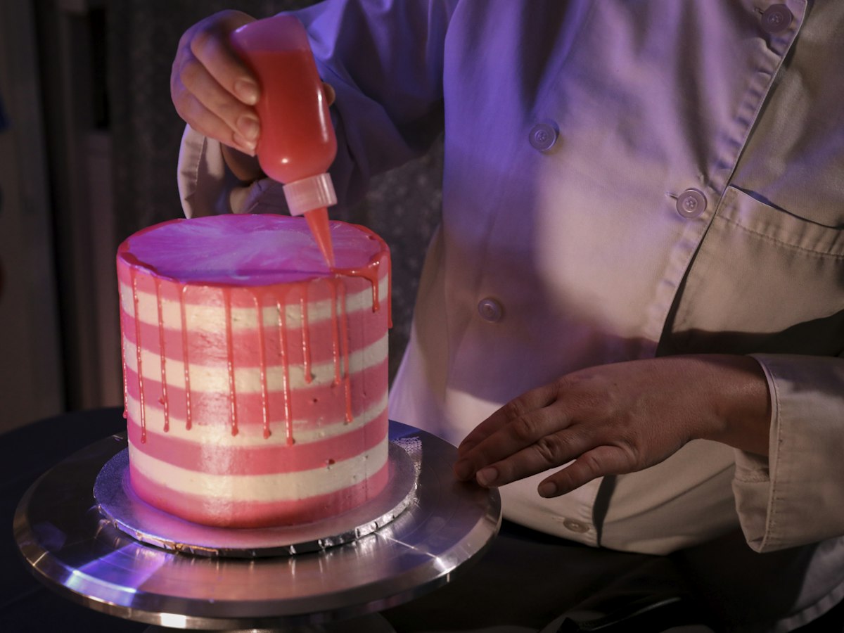 A custom celebration cake being finished by hand